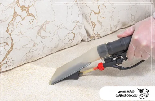 تنظيف مجالس رجال بالدمام 0557756533 شركة الفارس يد تقوم بتنظيف وسادة أريكة بلون بيج فاتح ومنقوش باستخدام جهاز استخلاص بفوهة عريضة لسحب الأوساخ.