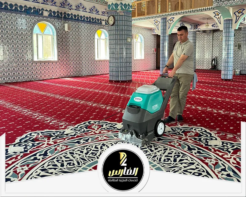 رجل ينظف سجادة في مسجد، يظهر اهتمامه بنظافة المكان وقدسيته.
