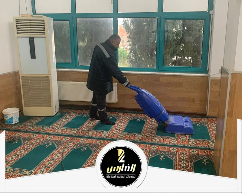 رجل ينظف غرفة باستخدام مكنسة كهربائية.