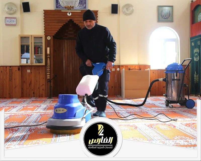 رجل يقوم بتنظيف غرفة بمكنسة كهربائية.