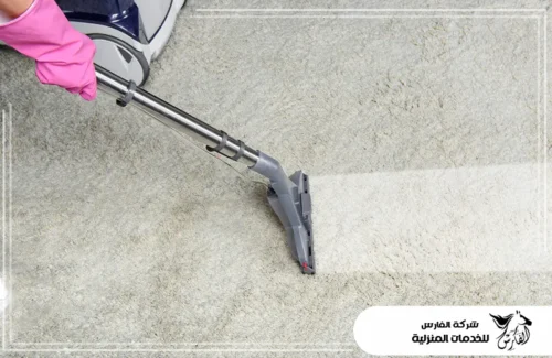 شركة غسيل سجاد شرق الرياض 0557756533 الفارس يد بقفاز وردي تستخدم مكنسة شفط تزيل الأوساخ من موكيت فاتح.