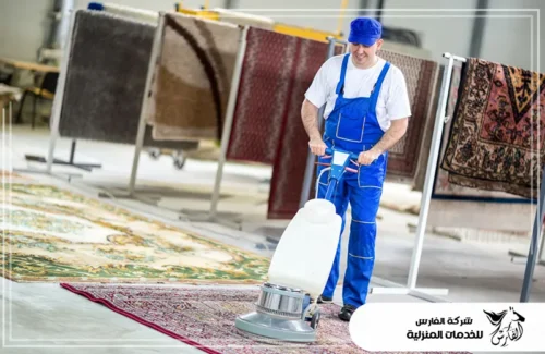 تنظيف الزيت من السجاد في الرياض 0557756533 الفارس عامل مبتسم يستخدم ماكينة تلميع وتنظيف كبيرة للسجاد في منشأة.