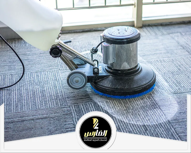 شخص يقوم بتنظيف موكيت باستخدام مكنسة كهربائية.
