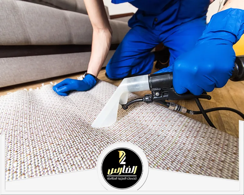  رجل يرتدي بدلة زرقاء يستخدم مكنسة كهربائية لتنظيف موكيت وسجاد.