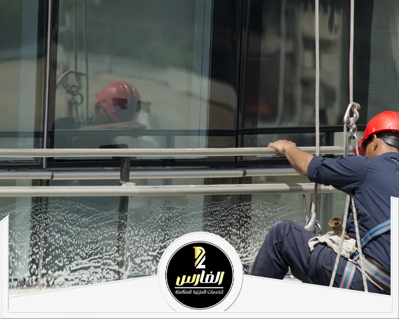شركة تنظيف واجهات زجاج بالرياض 0557756533 شركة الفارس تنظيف واجهة زجاجية بالرياض باستخدام الحبال مع عامل يعمل على تنظيف الزجاج من الأسطح العالية.